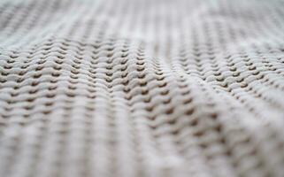 Nahansicht von das Textur von ein Beige Textil- werfen gemacht von natürlich Stoffe foto