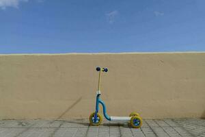 ein Blau und Gelb Roller gegen ein Gelb Mauer foto