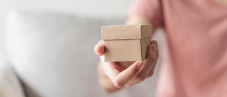 Nahaufnahme von Frauenhänden, die eine kleine Geschenkbox halten. kleine Geschenkbox in den Händen der Frau.