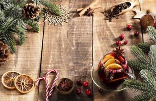 Weihnachtsglühwein mit Gewürzen auf einem rustikalen Holztisch. foto