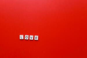 das Wort Liebe von hölzern Briefe auf ein rot Hintergrund. rundweg Valentinstag ist Tag foto