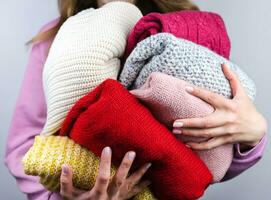 ein Frau hält hell warm Winter Pullover. Wandschrank Reinigung. Spenden. Nahansicht. selektiv Fokus. foto