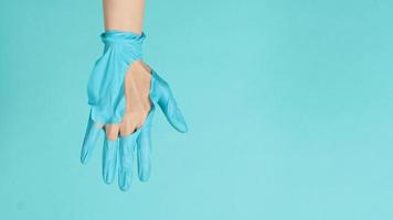 Nahaufnahme der Hand mit zerrissenen medizinischen Handschuhen oder zerrissenen Gummihandschuhen auf mintgrünem oder tiffanyblauem Hintergrund. foto