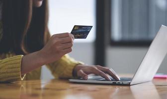 junge Frau, die Laptop verwendet und Kreditkarte hält, Online-Shopping-Konzept, Online-Zahlung mit Kreditkarte. foto