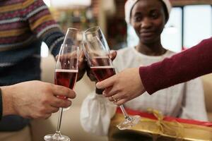 vielfältig Kollegen Toasten und Klirren Brille gefüllt mit funkelnd Wein, feiern Weihnachten zusammen. Angestellte Trinken Alkohol und Sprichwort Prost auf Neu Jahr Urlaub im Büro foto