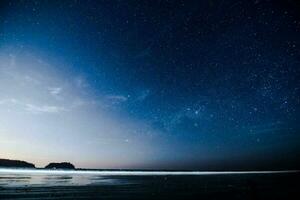 ein Person Stehen auf das Strand beim Nacht mit das Sterne über foto