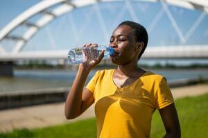 Frau Trinken Wasser während Übung draussen. foto