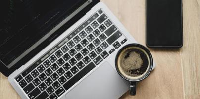 Kaffeetasse auf dem Laptop mit Aktienchart auf dem Bildschirm platziert, Draufsicht geschossen. foto