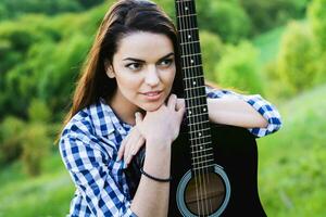 Mädchen auf ein Grün Wiese spielen Gitarre foto