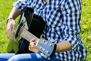 Mädchen auf ein Grün Wiese spielen Gitarre foto