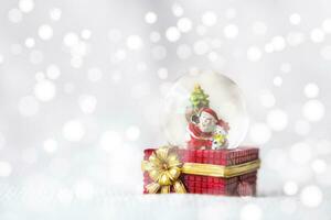 Weihnachten Bälle, Santa claus im ein Schnee Globus, und Kiefer Zapfen auf ein Weiß Tuch, einstellen gegen ein rot Hintergrund und exquisit Bokeh. Neu Jahr Feier Atmosphäre, Über von wichtig Tag. foto