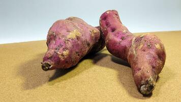 zwei lila Süss Kartoffeln auf ein Weiß Hintergrund foto