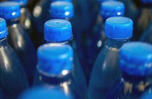 Nahansicht von groß Nummer von verpackt Blau Flaschen- Trinken Wasser mit Blau Caps.Trinken Wasser Flasche Hintergrund foto