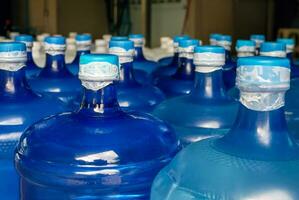 gefüttert oben Plastik groß Flaschen oder Blau Gallonen von gereinigt Trinken Wasser Innerhalb das Produktion Linie. Wasser trinken Fabrik foto