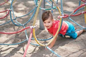 wenig Junge spielen im das Seil Netz auf das Spielplatz foto