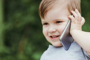 wenig Baby ist reden auf das Telefon im das Straße foto