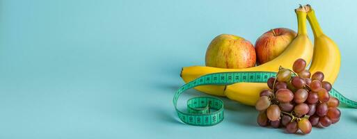 Messung Band und saftig Früchte auf ein Blau Hintergrund. das Konzept von Diät und richtig Ernährung. Banner Format foto