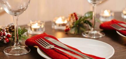 Weihnachtstischdekoration. Teller und Besteck auf roter Serviette. kerzen, die an heiligabend auf dem tisch brennen. Vorbereitung für das festliche Abendessen. foto