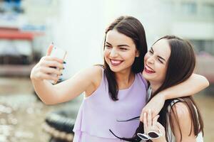 zwei schön Schwestern tun Selfie auf das Straße foto