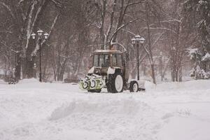 das Traktor reinigt das Schnee im das Park foto