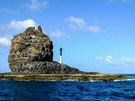 ein Leuchtturm auf ein felsig Insel im das Mitte von das Ozean foto