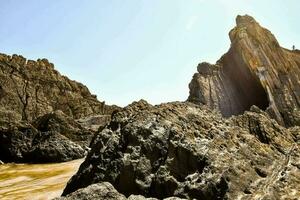 das Sonne scheint durch das Felsen auf das Strand foto