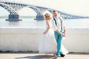 das Braut und Bräutigam sind fotografiert auf das Hintergrund von das Brücke foto