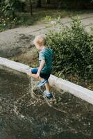 wenig Junge Springen im ein Pfütze im Sommer- foto