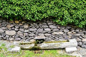 ein Stein Mauer mit ein Wasser Brunnen im Vorderseite von es foto