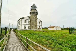 ein hölzern Gehweg führt zu ein Leuchtturm Nächster zu ein Weiß Gebäude foto