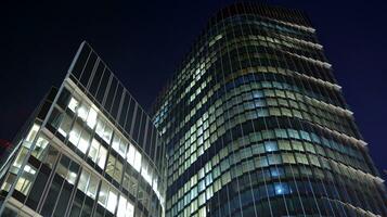Muster von Büro Gebäude Fenster beleuchtet beim Nacht. Glas die Architektur , Unternehmen Gebäude beim Nacht - - Geschäft Konzept. foto
