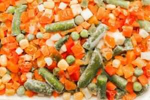 gefroren Gemüse Möhren, Erbsen, Bohnen im ein Teller foto