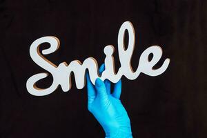 das Inschrift Lächeln im das Hände von ein Arzt der Chirurg Zahnarzt foto
