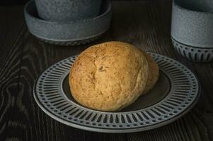 ein gebacken Brot auf ein Teller mit ein Tasse von Tee foto