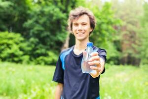 Sportler mit ein Flasche von Wasser nach Laufen draußen im Park foto