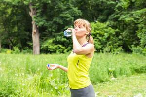 Fitness-Frau Trinkwasser aus der Flasche. foto