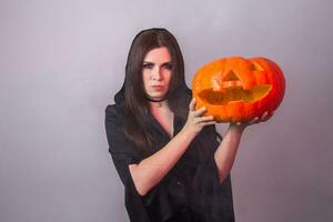 Halloween Hexe halten ein Orange Kürbis Jack Ö Laterne mit Rauch foto