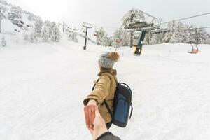 Folgen mich Mädchen halten Freund Hand im Winter Schnee Natur. Ski Resort auf das Hintergrund foto