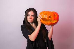 Frau wie Hexe ist Stehen mit das Kürbis im das Studio. Halloween und Karneval Konzept foto