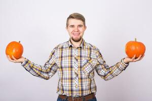 Porträt von ein komisch Farmer halten ein Kürbisse auf ein Licht Hintergrund Studio foto