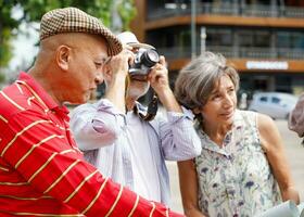 Senior Chinesisch Tourist mit seine Freund europäisch Tourist Paar Gehen Tour und nehmen Fotos im das Stadt