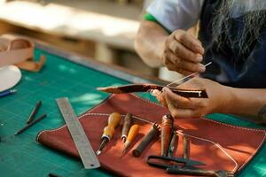 Nahansicht und Ernte Hände von Leder Handwerker ist Arbeiten schwer zu nähen ein Leder Produkt zum ein Kunde. foto