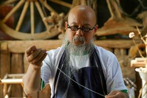 Nahansicht Hand von asiatisch Leder Handwerker ist vorsichtig zu nähen ein Leder Gürtel zum ein Kunde., Leder Handwerker Konzept. foto