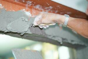 Nahansicht Hände von Baumeister halten Granatwerfer schwenken und Verputzen Wände mit Zement im Konstruktion Seite? ˅. foto