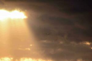 ein Flugzeug fliegend durch das Wolken mit Sonnenstrahlen Kommen durch foto