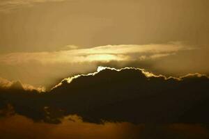 ein Silhouette von ein Wolke mit das Sonne leuchtenden durch es foto