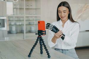 froh Frau mit ein bionisch Arm filmen ein vlog, präsentieren das nahtlos Mischung von Täglich Leben und fortgeschritten Technik foto