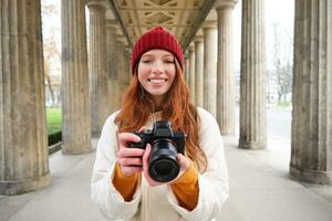 lächelnd Tourist Fotograf, nimmt Bild während ihr Reise, hält Fachmann Kamera und macht Fotos