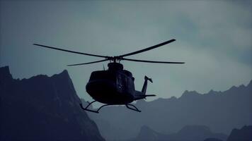 ein schwarz Hubschrauber fliegend Über ein Berg Angebot foto