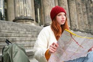 schön jung Frau, Reisender mit Rucksack hält Papier Karte, erforscht Stadt Besichtigung, Pläne Route zum Tourismus Beliebt Sehenswürdigkeiten foto